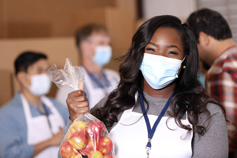 Woman working at food pantry, holding apples