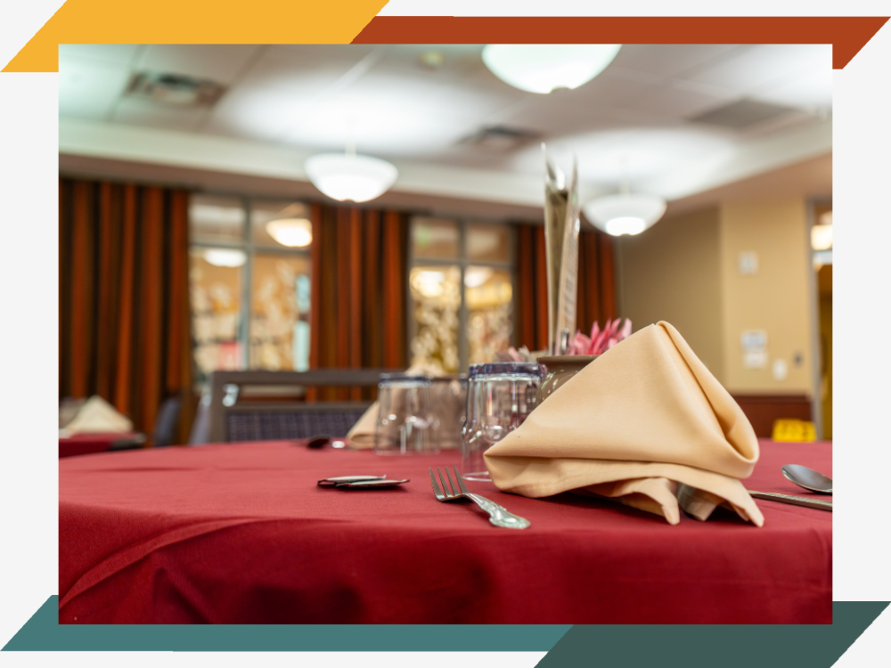 Neatly folded napkin and clean silverware on a dining room table.